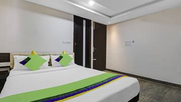 A hotel room with a bed, a nightstand, a wardrobe, and a door.