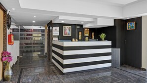 A reception desk with a black and white striped design, a fire extinguisher, and a sign indicating no smoking. - Treebo JJ Residency (Bengaluru)
