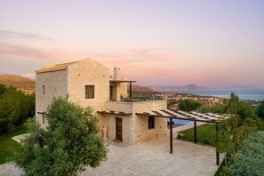 Une maison en pierre dotée d’un balcon, d’une pergola et offrant une vue sur la mer.
