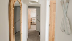 A hallway with a wooden archway, a white ceiling light, and a wooden door. - A Mor (Llanfairpwllgwyngyll)
