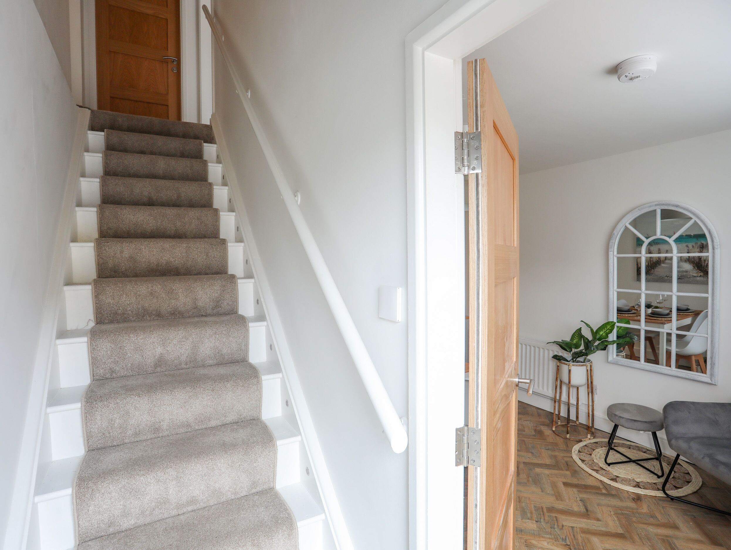Una escalera con peldaños alfombrados, una puerta de madera y un comedor con una mesa y sillas.