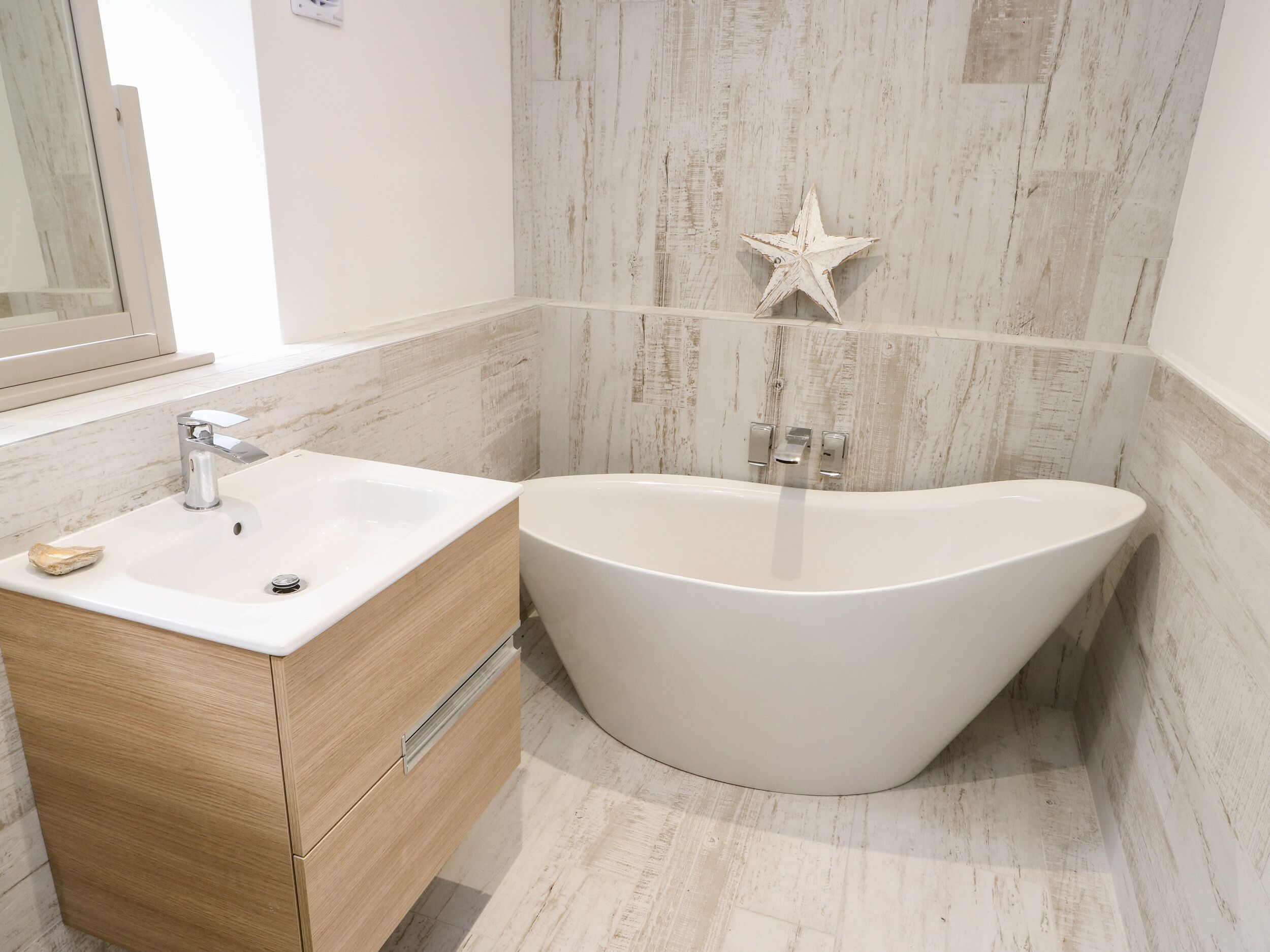 A modern bathroom with a freestanding bathtub, a vanity with a mirror, and a star decoration on the wall.