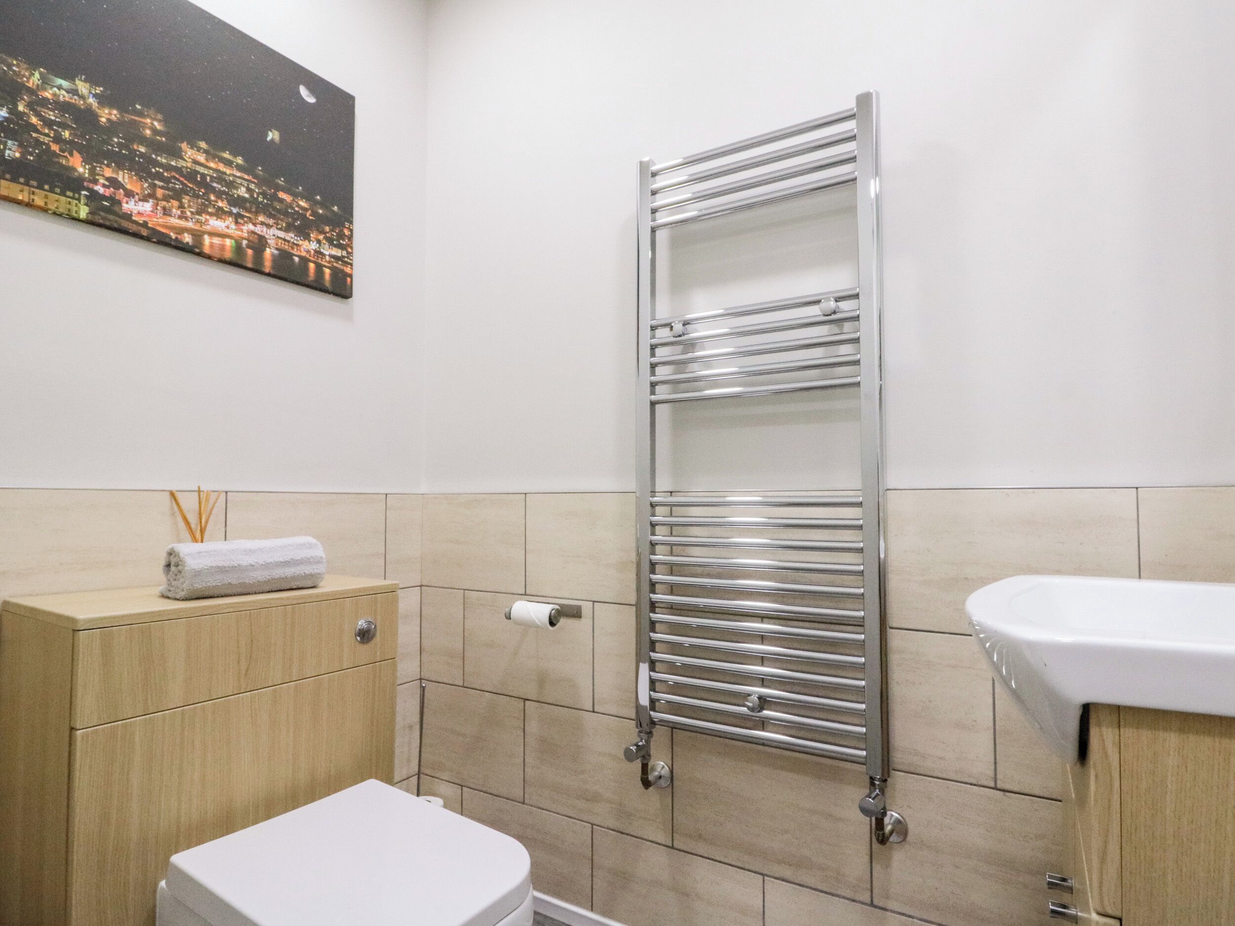 A modern bathroom with a toilet, sink, and a towel rack.