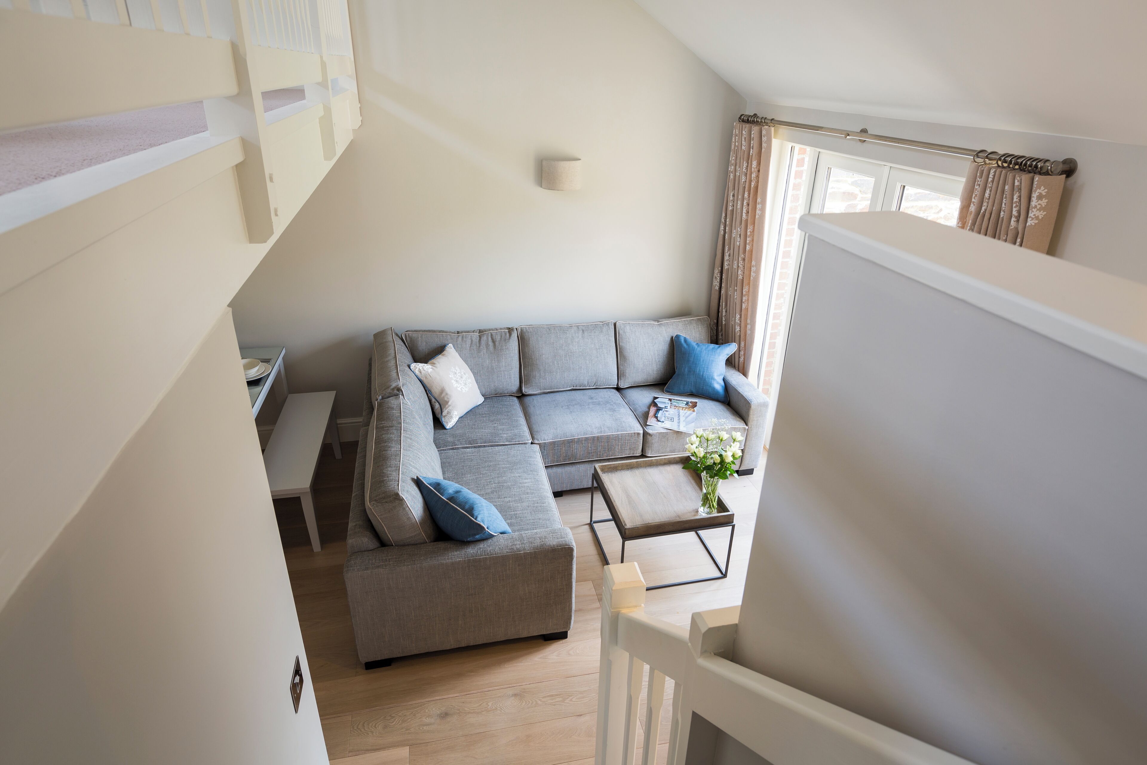 A modern living room with a grey sectional sofa, a small coffee table, and a white bench.