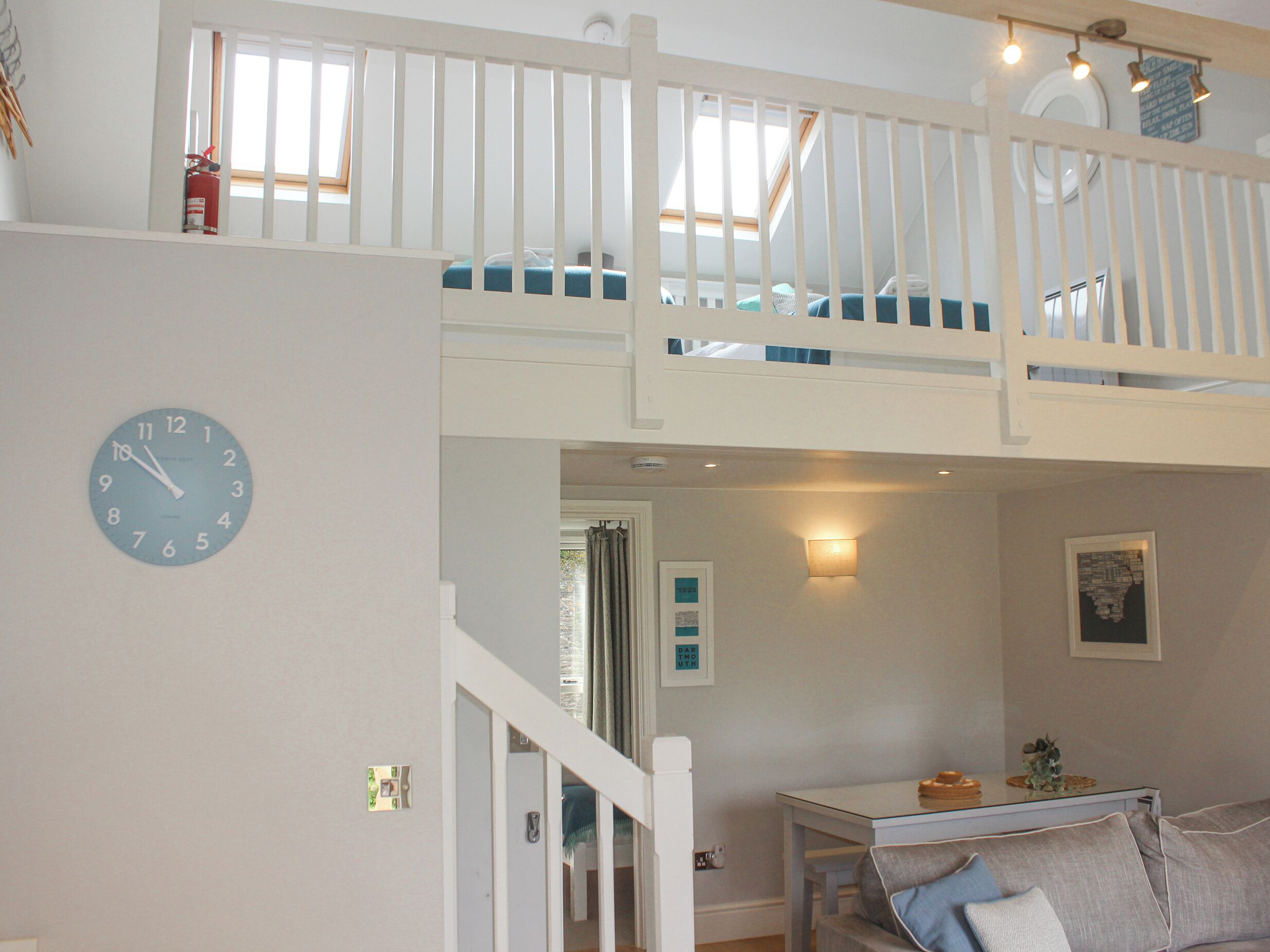 A room with a loft bed, a dining table, and a clock on the wall.