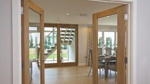 A spacious room with a wooden floor, a dining area with a table and chairs, and a staircase leading to an outdoor area. - 3 The Drive, Hillfield Village (Dartmouth)