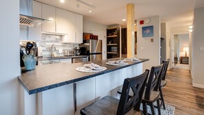 Une cuisine moderne dotée d’un îlot central, d’appareils électroménagers en acier inoxydable et d’un coin repas avec des chaises.