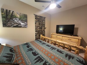 Relax in this inviting bedroom with a comfortable bed, flat-screen TV, and a serene forest view.
