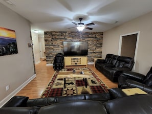 Relax in this stylish living room with a flat-screen TV, black leather sofa, and a massage chair.