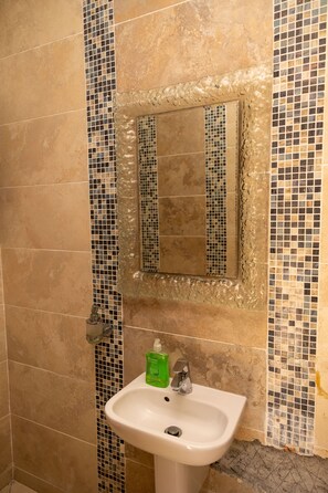 A bathroom with a sink, mirror, and mosaic tile walls.