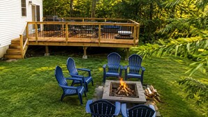 A backyard with a deck, outdoor seating, and a fire pit. - Spacious Home for 14 Guests Near Lake Winnisquam – Close to Everything! (Sanbornton)