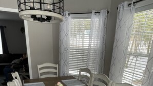 A dining room with a wooden table, white chairs, and a chandelier. - Spacious Home for 14 Guests Near Lake Winnisquam – Close to Everything! (Sanbornton)