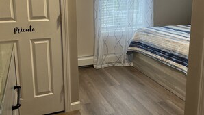 A bedroom with a bed, a window with curtains, a door labeled "Private," and a painting on the wall. - Spacious Home for 14 Guests Near Lake Winnisquam – Close to Everything! (Sanbornton)