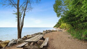 A wooden picnic table by a rocky shoreline with a clear view of the sea. - Glennhouse Getaway (South Haven)