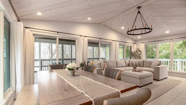 A spacious room with a long wooden table, a large sofa, and a chandelier. - Glennhouse Getaway (South Haven)