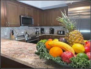 Una cocina con armarios de madera, encimera de granito y refrigerador de acero inoxidable.