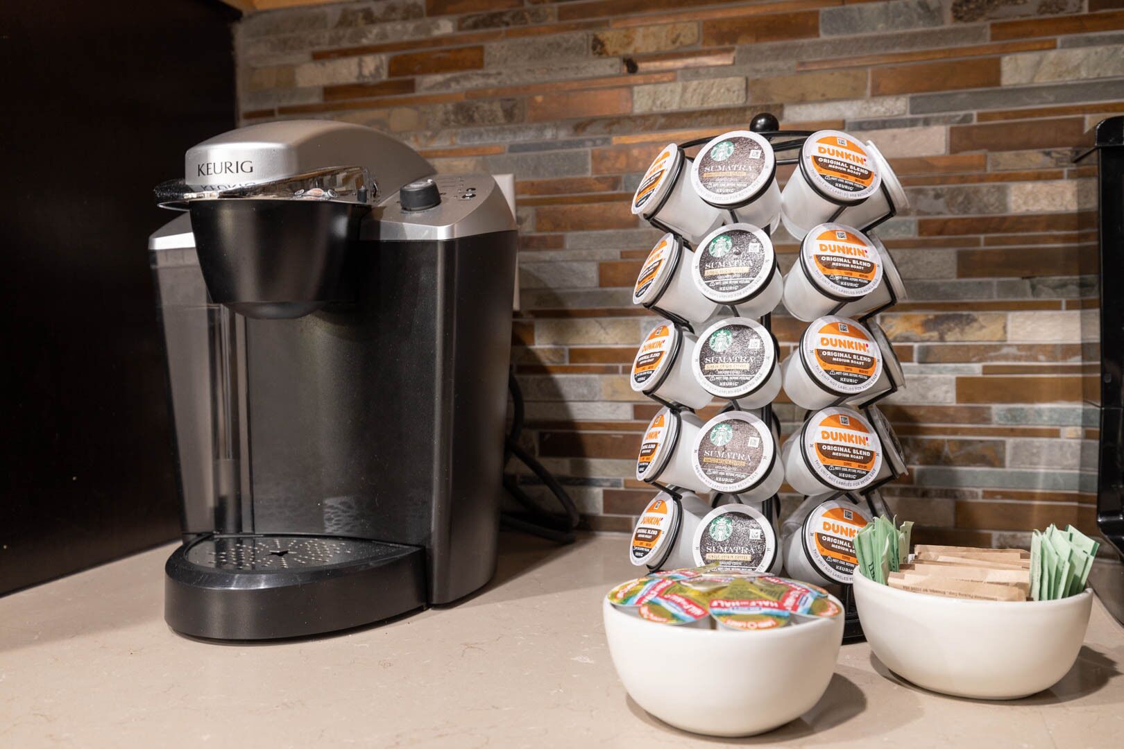 A Keurig coffee maker and a stack of Dunkin' coffee pods on a countertop.