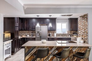 Una cocina moderna con armarios de madera oscura, electrodomésticos de acero inoxidable y una isla central con taburetes de bar.