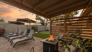 Een terras buiten met lounge fauteuils, een vuurkorf en potplanten.