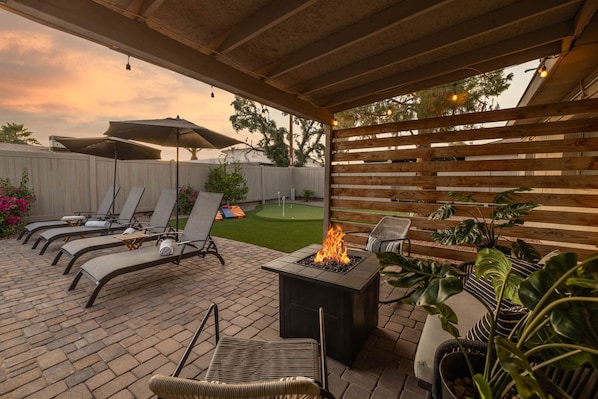 Un patio al aire libre con sillones de descanso, una chimenea y plantas en macetas.