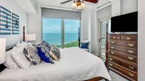 A bedroom with a large bed, a ceiling fan, a dresser, and a TV. - Portofino Tower 1 | Sound View Escape (Pensacola Beach)