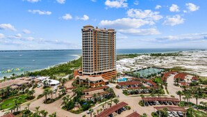 A high-rise hotel with a pool, beach view, and parking area. - Portofino Tower 1 | Sound View Escape (Pensacola Beach)