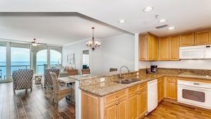 A modern kitchen with granite countertops, wooden cabinets, and a built-in oven. - Portofino Tower 1 | Sound View Escape (Pensacola Beach)