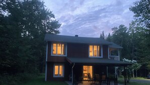 Ein zweistöckiges Haus mit einer Veranda und einem Rasen.