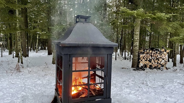 Ein mit Schnee bedeckter Wald, ein Metalllaterne strahlt warmes Licht.