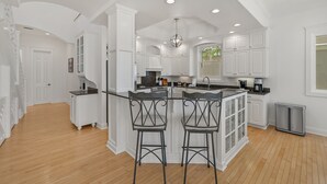A spacious kitchen with white cabinetry, a central island with bar stools, and a large window providing natural light. - Gulf Front Updated Coastal Home 1 mile from Seaside (Santa Rosa Beach)