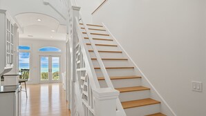 A staircase with white railings and wooden steps leading to a balcony with a view of the ocean. - Gulf Front Updated Coastal Home 1 mile from Seaside (Santa Rosa Beach)