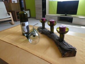 Uma garrafa de vinho, um copo e três velas sobre uma mesa de madeira.