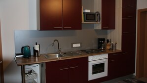 Una cucina compatta con mobili scuri, un forno a microonde, una macchina del caffè e un lavello.