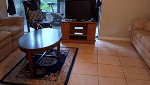 Un salon avec un canapé, une table basse et un téléviseur posé sur un meuble.