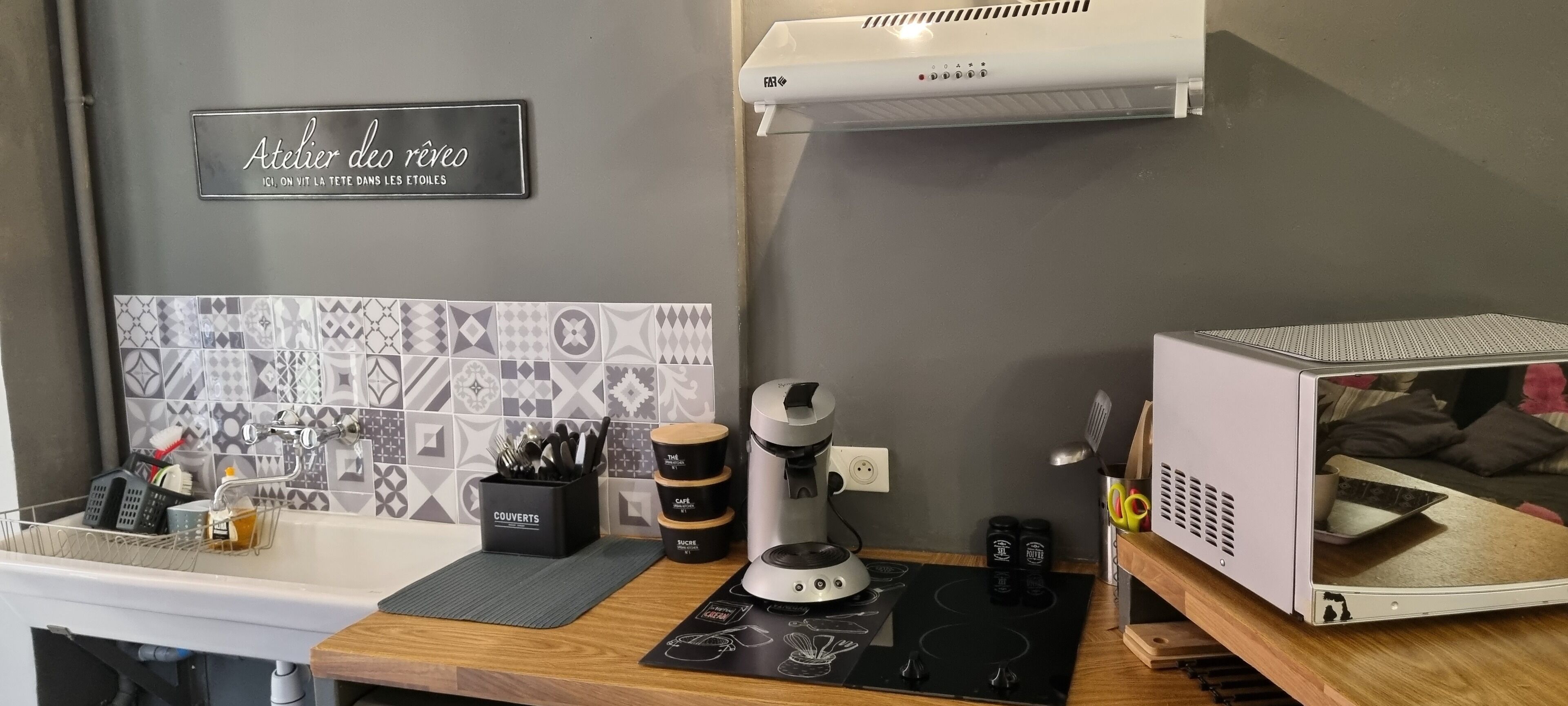 Una cocina de diseño moderno, con un lavamanos, una cafetera y un microondas.