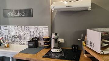 Una cocina de diseño moderno, con un lavamanos, una cafetera y un microondas.