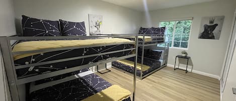 Een slaapkamer met een stapelbed, een raam, een tafeltje en een foto aan de muur.
