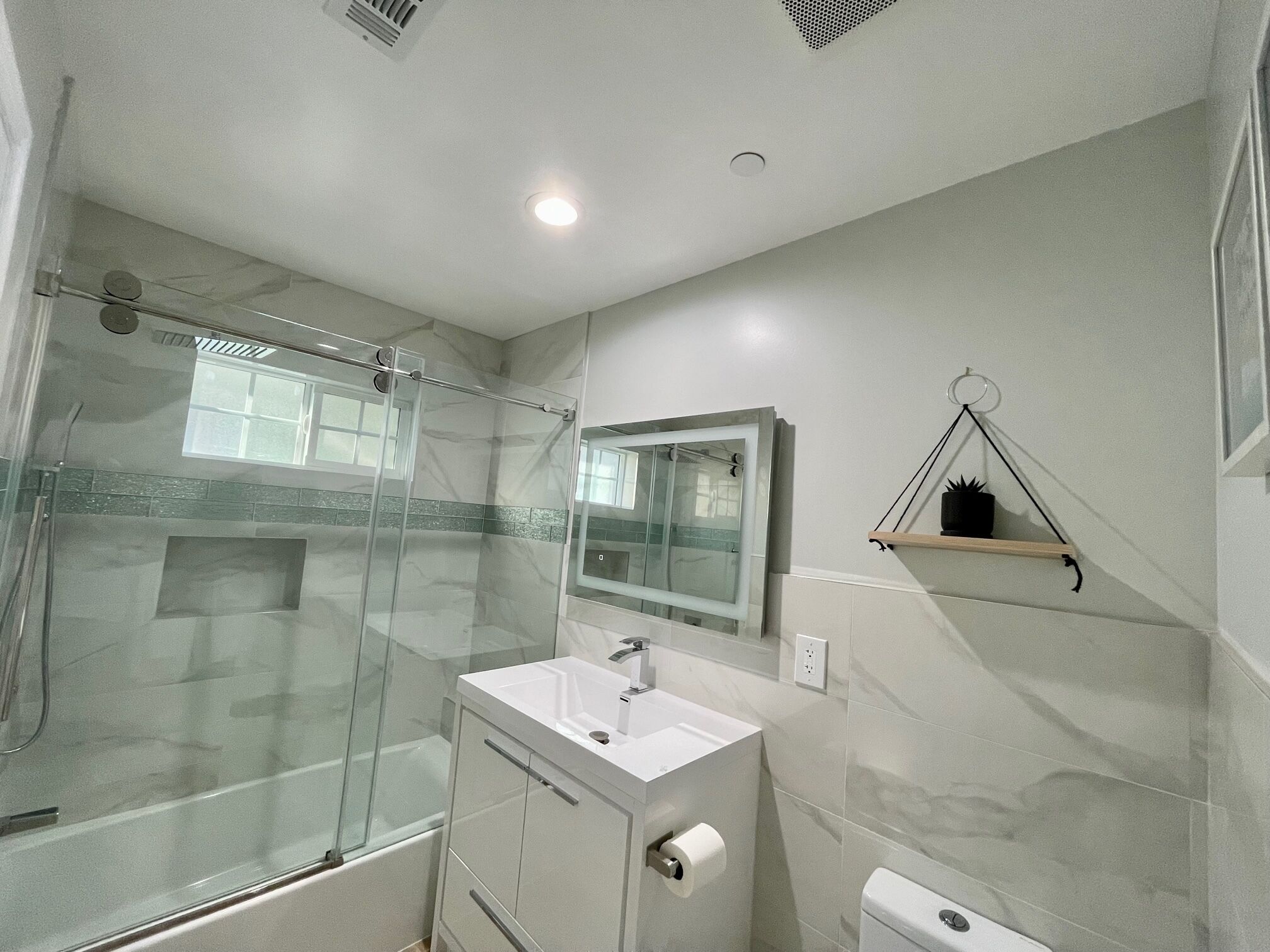 A modern bathroom with a glass-enclosed shower, a white sink, and a mirror above it.