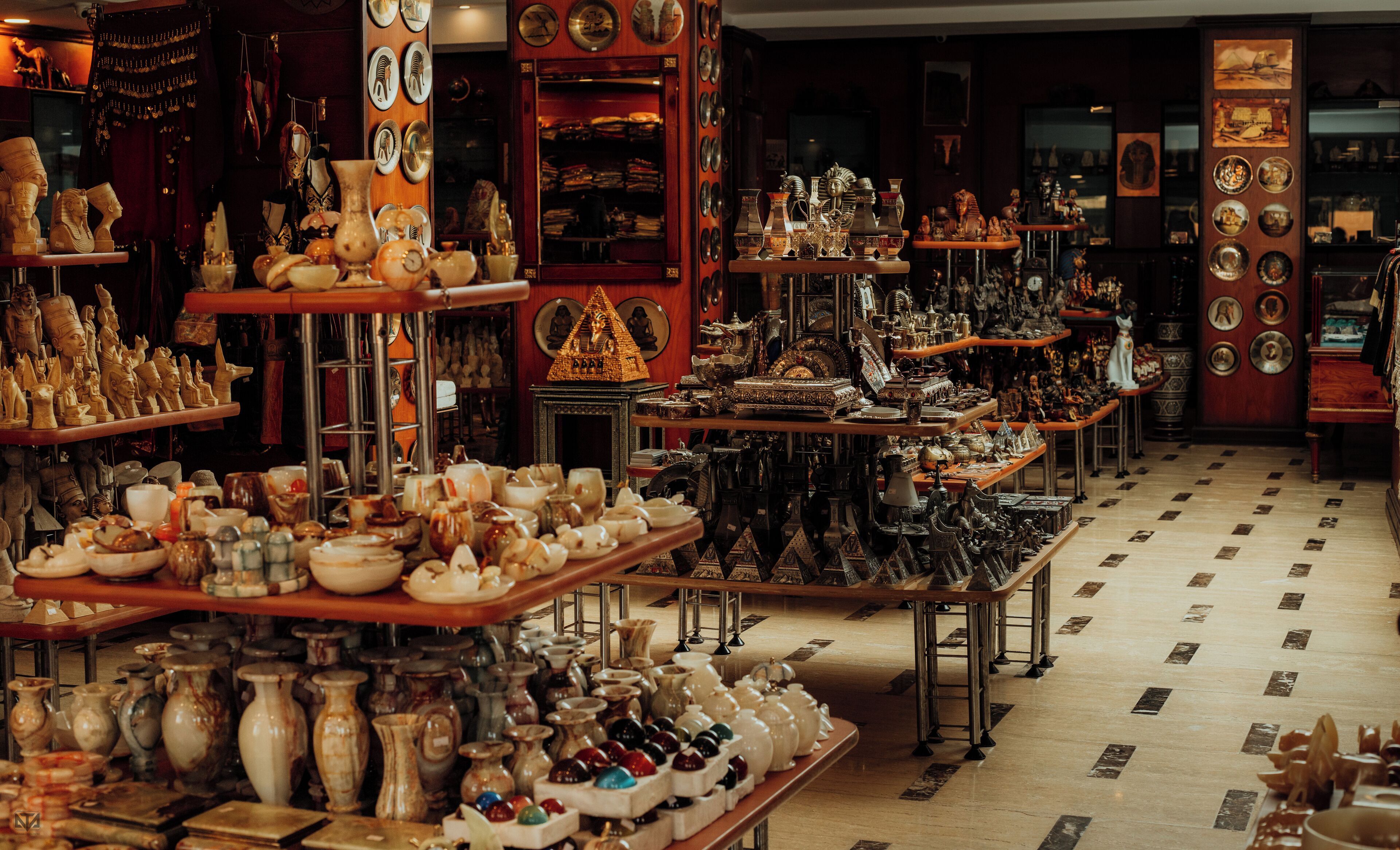 Een winkel vol keramiek en decoratieve objecten, uitgestald op planken en tafels.