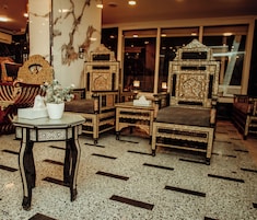 Un intérieur traditionnel agrémenté de meubles décoratifs, notamment un fauteuil à haut dossier et une petite table sur laquelle est posée une plante en pot.