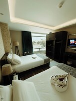 Habitación de hotel con cama, televisión, escritorio y ventana con vistas.