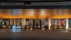 L’entrée d’un hôtel au design moderne, avec une enseigne « EAST » bien visible, de grandes fenêtres et une façade bien éclairée.