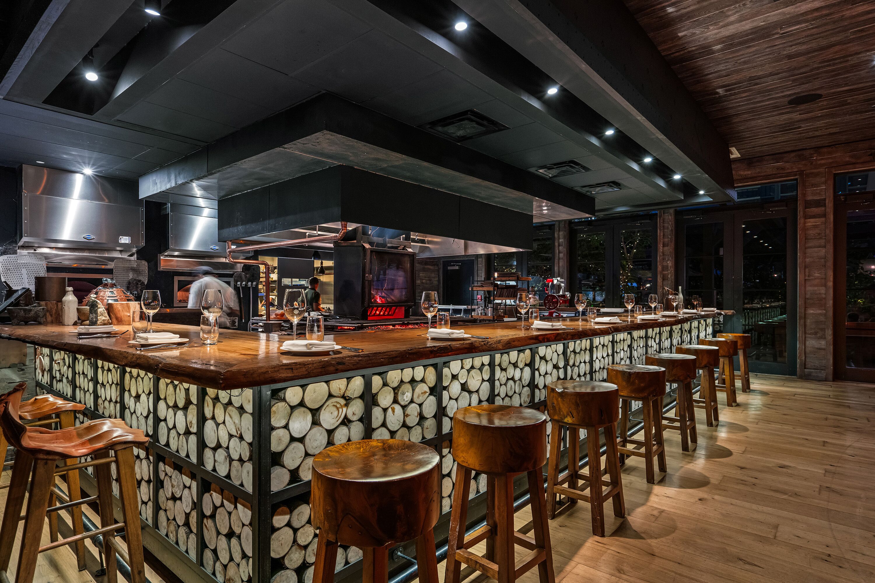 A bar area with a long counter, stools, and a kitchen in the background.