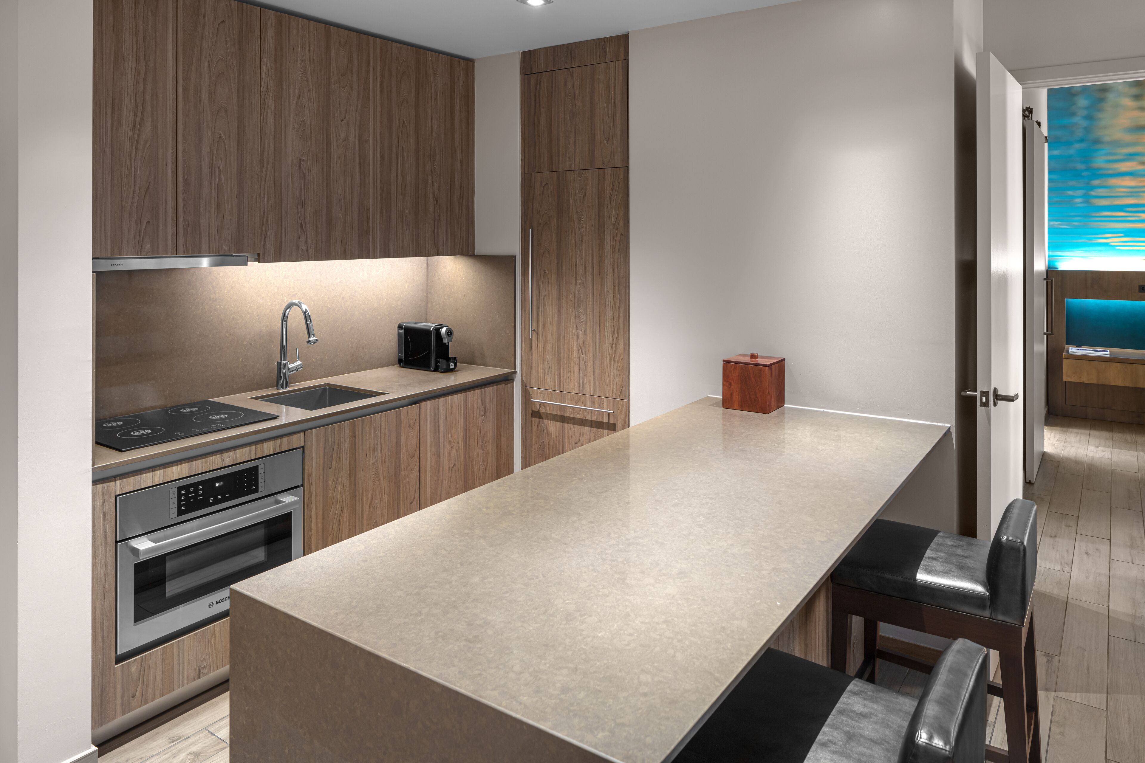 Une cuisine moderne avec des meubles en bois, des appareils en acier inoxydable et un grand îlot central doté de sièges.