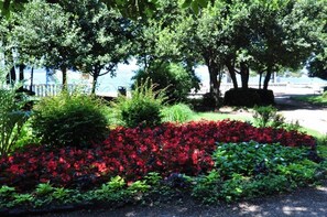 Stroll through the tranquil garden, surrounded by vibrant flowers and lush foliage, with a serene body of water in the distance.