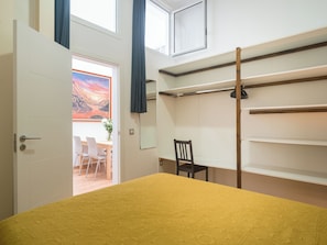 A room with a bed, a desk, a chair, a painting, and a window.