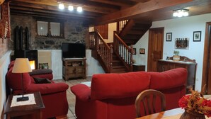 A cozy living room with red sofas, a wooden table, and a TV stand.