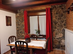 Un comedor con pared de piedra, techo de madera y una mesa con sillas.