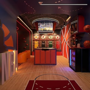 A basketball-themed room with a large screen, shelves with jerseys, and a basketball hoop.