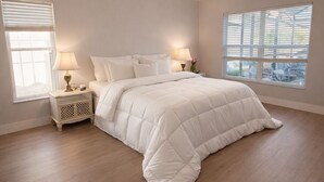 Una camera da letto con un letto grande, due comodini con lampade, un lampadario e una finestra con persiane.